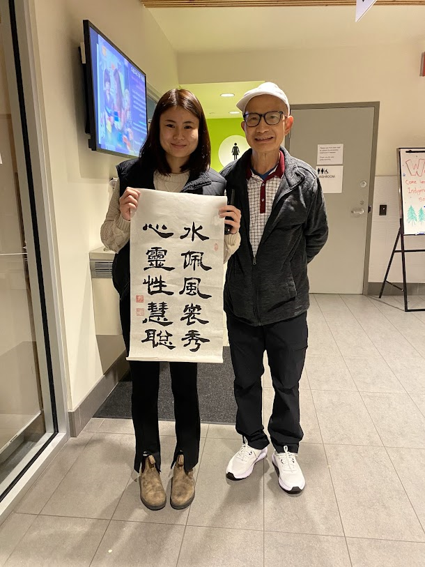 張士方在城市中心社區(qū)當(dāng)書法班義工，為經(jīng)理撰書嵌名聯(lián).png